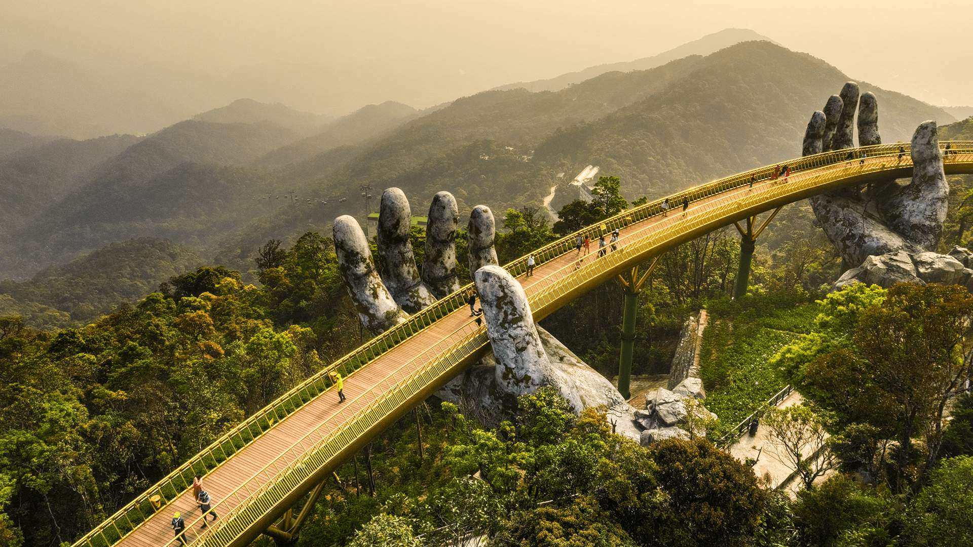 The Golden Bridge in Vietnam is a stunning pedestrian bridge held by giant stone hands, located in Ba Na Hills, which also features a scenic cable car ride and a charming French-style village.